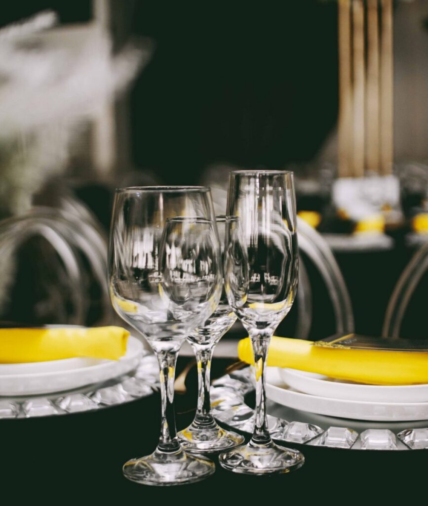 Sophisticated table arrangement featuring yellow napkins, wine glasses, and black linens.