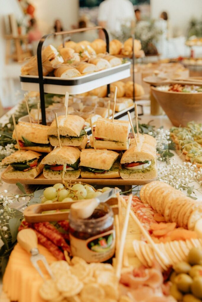 A vibrant buffet spread featuring sandwiches, crackers, meats, cheeses, and buns, perfect for events and gatherings.
